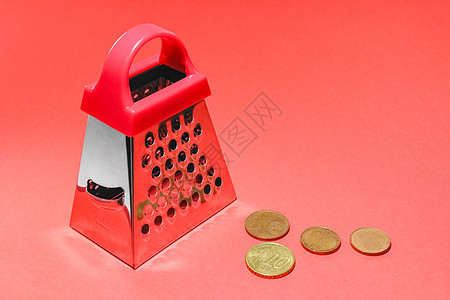 用欧元硬币在红色背景上的厨房磨刀图片