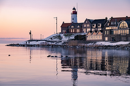 Urk 的冬天 Urk 灯塔旁的堤坝和海滩在冬天被雪覆盖 灯塔旁的日落地标港口村庄旅行降雪旅游季节场景天气雪花图片