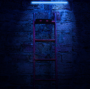 晚上在砖墙壁背景上用金属楼梯和亮亮的蓝月亮灯图片