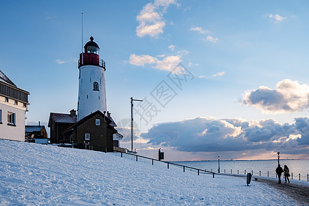 Urk 的冬天 Urk 灯塔旁的堤坝和海滩在冬天被雪覆盖 灯塔旁的日落场景村庄传统旅游降雪海岸天空假期季节港口图片