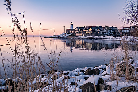 Urk 的冬天 Urk 灯塔旁的堤坝和海滩在冬天被雪覆盖 灯塔旁的日落天气旅游雪花海岸降雪假期季节传统村庄天空图片