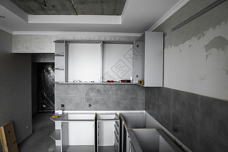 没有家具立面 mdf 的定制厨柜安装 灰色模块化厨房由刨花板材料制成 在厨房的不同安装阶段 地板和墙壁上铺有灰色瓷砖家居贮存内阁图片