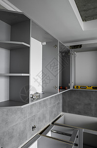 没有家具立面 mdf 的定制厨柜安装 灰色模块化厨房由刨花板材料制成 在厨房的不同安装阶段 地板和墙壁上铺有灰色瓷砖贮存战线器具图片