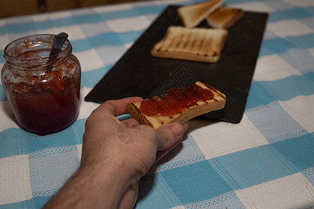 手握着一块吐司和果酱早餐盘子小吃营养浆果食物午餐黄油小麦花生图片