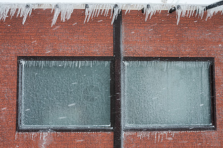 建筑物的墙壁和窗户上盖着冰和冰柱图片