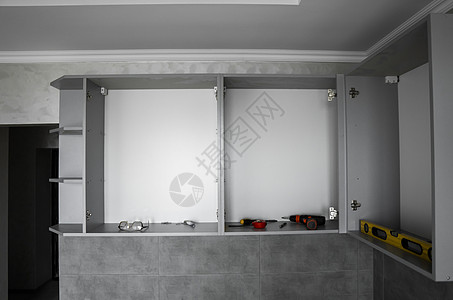 没有家具立面 mdf 的定制厨柜安装 灰色模块化厨房由刨花板材料制成 在厨房的不同安装阶段 地板和墙壁上铺有灰色瓷砖战线房子工具图片