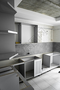 没有家具立面 mdf 的定制厨柜安装 灰色模块化厨房由刨花板材料制成 在厨房的不同安装阶段 地板和墙壁上铺有灰色瓷砖工具装修贮存图片