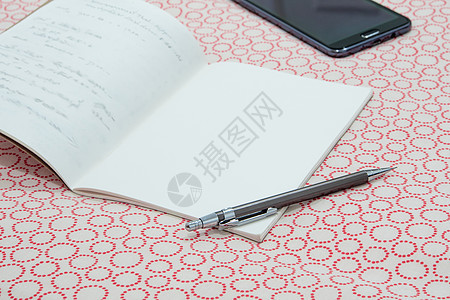 一张笔记本和一张笔 放在桌布上背景图片