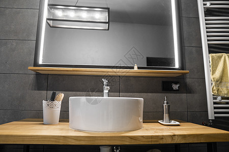 洗手间内部墙上有灰瓷砖 有时髦的圆水槽和橡树木工作台 在浴室的内部是最小的镜子龙头盆地奢华洗手盆卫生植物圆形房子房间图片