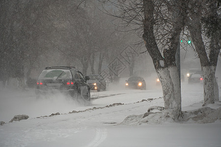冬天 在暴风雪 暴风雪或降雪中 城市的恶劣天气下 积雪覆盖的道路上有汽车 北方的极端冬季天气条件 汽车驶过城市积雪覆盖的街道冰川图片