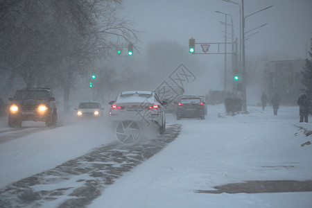 冬天 在暴风雪 暴风雪或降雪中 城市的恶劣天气下 积雪覆盖的道路上有汽车 北方的极端冬季天气条件 汽车驶过城市积雪覆盖的街道季节图片