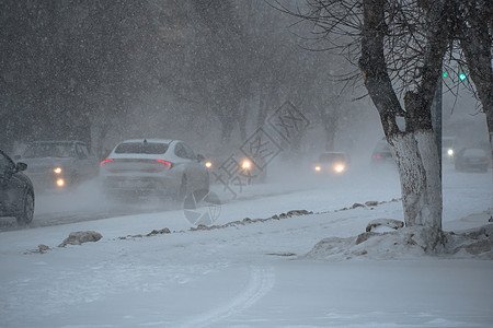 冬天 在暴风雪 暴风雪或降雪中 城市的恶劣天气下 积雪覆盖的道路上有汽车 北方的极端冬季天气条件 汽车驶过城市积雪覆盖的街道轿车图片