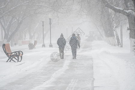 一条积雪覆盖的道路 冬天在城市的恶劣天气下 人们在暴风雪 暴风雪或降雪中 北方的极端冬季天气条件 人们在大雪中穿过街道民众气象气图片