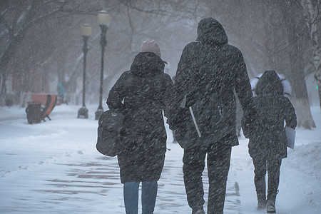 一条积雪覆盖的道路 冬天在城市的恶劣天气下 人们在暴风雪 暴风雪或降雪中 北方的极端冬季天气条件 人们在大雪中穿过街道服务寒意风图片