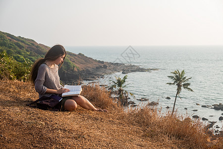 一个亚洲女人 一本有海观的书长发天空爱好成人旅游女性小说书旅行棕色晴天图片