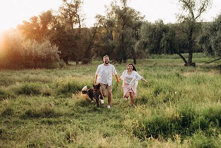 大狗跟一个男人和一个女孩散步朋友绿色乐趣皮带打猎跑步活力男人夫妻女孩背景图片