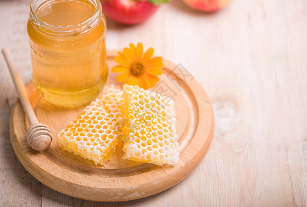 蜜蜂座背景的蜜糖 玻璃罐和蜂窝蜡中的蜜砖蜂巢滴水毛毛生物食物金子细雨玻璃饮食养蜂业图片