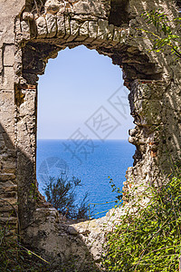 透过蓝色海景上的旧的废弃破旧建筑观察石头历史旅行堡垒天空窗户房子建筑学历史性走廊图片