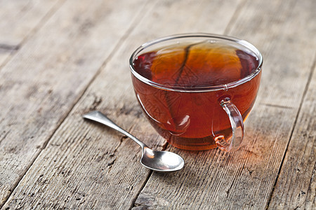 一杯新鲜茶和老汤匙 在生锈的木制餐桌背景上图片