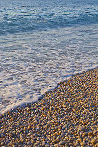 海边有泥石 蓝色的蒂罗亨尼亚海浪太阳阳光支撑鹅卵石岩石海洋石头晴天旅行海滨图片