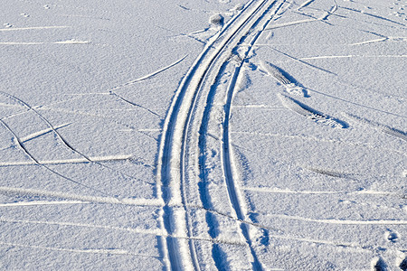 近距离观察积雪覆盖的街道上的轮胎痕迹曲目粉雪阴影雪堆蓝色天气曲线小路阳光运输图片