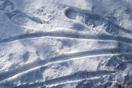 近距离观察积雪覆盖的街道上的轮胎痕迹蓝色季节阴影曲目小路阳光运输牵引力天气粉雪图片