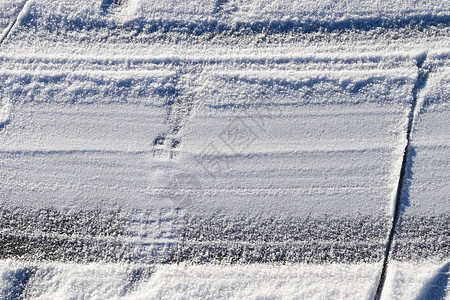 近距离观察积雪覆盖的街道上的轮胎痕迹蓝色天气雪堆季节曲线阳光运输粉雪胎迹摄影图片