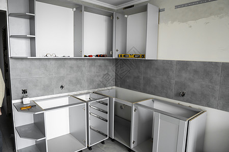 没有家具立面 mdf 的定制厨柜安装 灰色模块化厨房由刨花板材料制成 在厨房的不同安装阶段 地板和墙壁上铺有灰色瓷砖橱柜地面战线图片