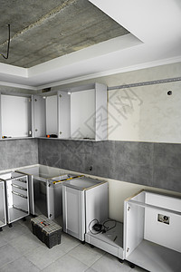 没有家具立面 mdf 的定制厨柜安装 灰色模块化厨房由刨花板材料制成 在厨房的不同安装阶段 地板和墙壁上铺有灰色瓷砖风俗贮存战线图片