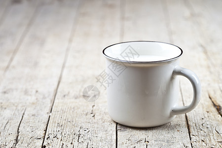 白色陶瓷杯上的新鲜牛奶 在生锈的木制桌子背景上图片