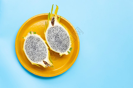 黄皮卡哈亚或蓝底黄色盘子上的龙果营养菠萝水果热带种子叶子柠檬情调维生素饮食图片