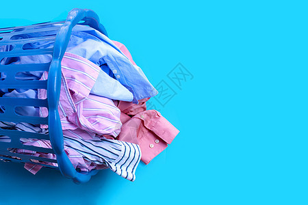 穿着蓝色背景的洗衣篮的衣物衣服工作洗涤剂篮子肥皂粉末搪瓷洗衣店织物家务图片