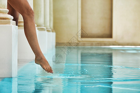 低层妇女 通过游泳池边感觉水温;图片