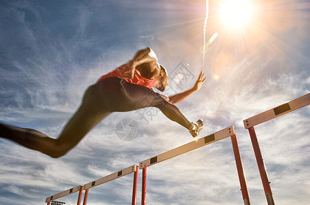 运行者跳过障碍 低角度视图晴天运行竞走女性短跑双臂运动员女人奉献跨栏图片