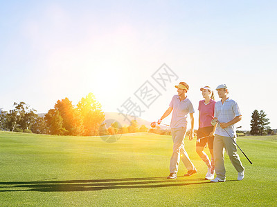 青年高尔夫球员在高尔夫球场上行走的肖像微笑玩家俱乐部晴天竞赛成人场地男人课程女性图片