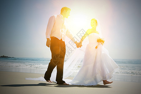 整群新婚夫妇在海滩上散步时手牵手新郎男人庆典婚礼花朵天空燕尾服面纱种族风俗图片