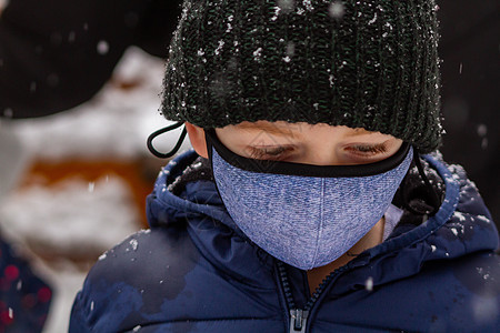 一个戴着黑帽子的男孩 在雪中戴面罩图片