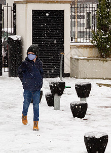 一个男孩在雪中行走图片