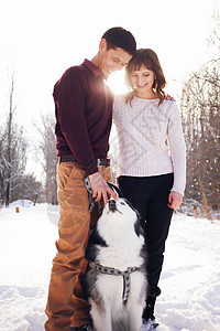 冬天在公园里 小夫妇和西比莉安哈斯基狗旅行快乐幸福女孩女士男人家庭假期树木森林图片