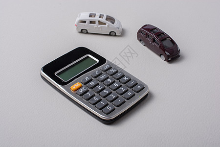 白色计算器旁边的小小汽车大小玩具金融车轮办公室展示教育引擎速度保险车辆图片