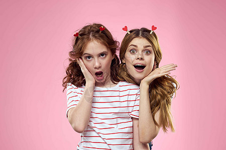 幸福的姐妹们在粉红背景上玩得开心 头上有心形衣帽乐趣女孩喜悦女孩们女性友谊裙子孩子潮人工作室图片