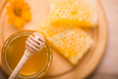 蜜蜂座背景的蜜糖 玻璃罐和蜂窝蜡中的蜜砖营养药品生物细雨食物饮食蜜蜂金子毛毛液体图片
