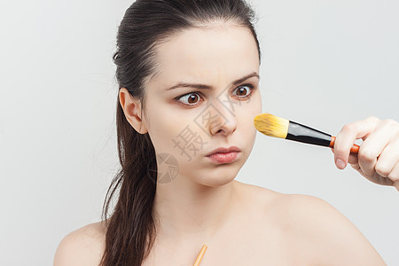 可爱裸露的棕发美女 在脸部剪裁视图上化妆程序福利皮肤沙龙奶油刷子皮革美容师女孩药品图片