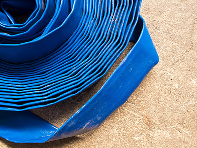 混凝土地板上滚滚的罐子软管店铺管道缠绕蓝色地面线圈帆布折叠管子图片