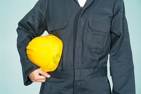 站在蓝色覆盖层的工人 拿着黄色硬头巾工作服工程师手臂检查员头盔塑料技术员制服男性制造业图片
