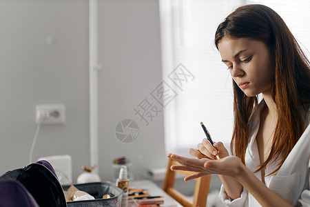 妇女拿着铅笔 坐在桌子上做化妆品的眼线画像基金会图片
