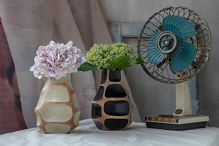 两个手工制作的木花瓶和旧水泥墙白色纹理桌布上的复古扇子中的绿色和紫色花束制品花朵作品陶瓷艺术装饰家居木头工艺陶器图片