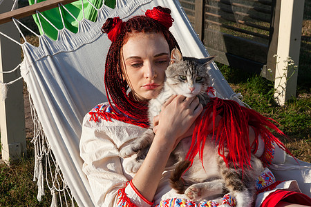 与猫玩的年轻女人眼睛毛皮裙子辫子哺乳动物友谊小猫猫科冲孔头发图片