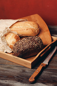 餐盘上的黑麦面包和红背景的桌子上一把利刃刀面粉早餐木头健康饮食农业谷物小麦饮食食物脆皮图片