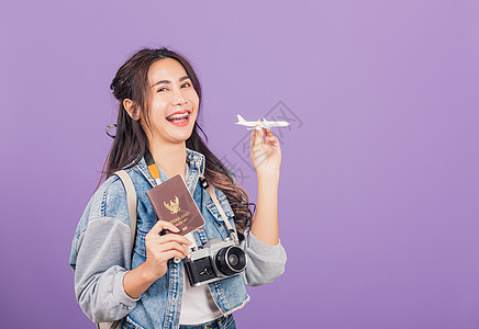 妇女在暑假时笑得兴奋 手持飞机玩具 护照和旧照相机飞机场文档女孩手势紫色牛仔布折扣冒险工作室女士图片